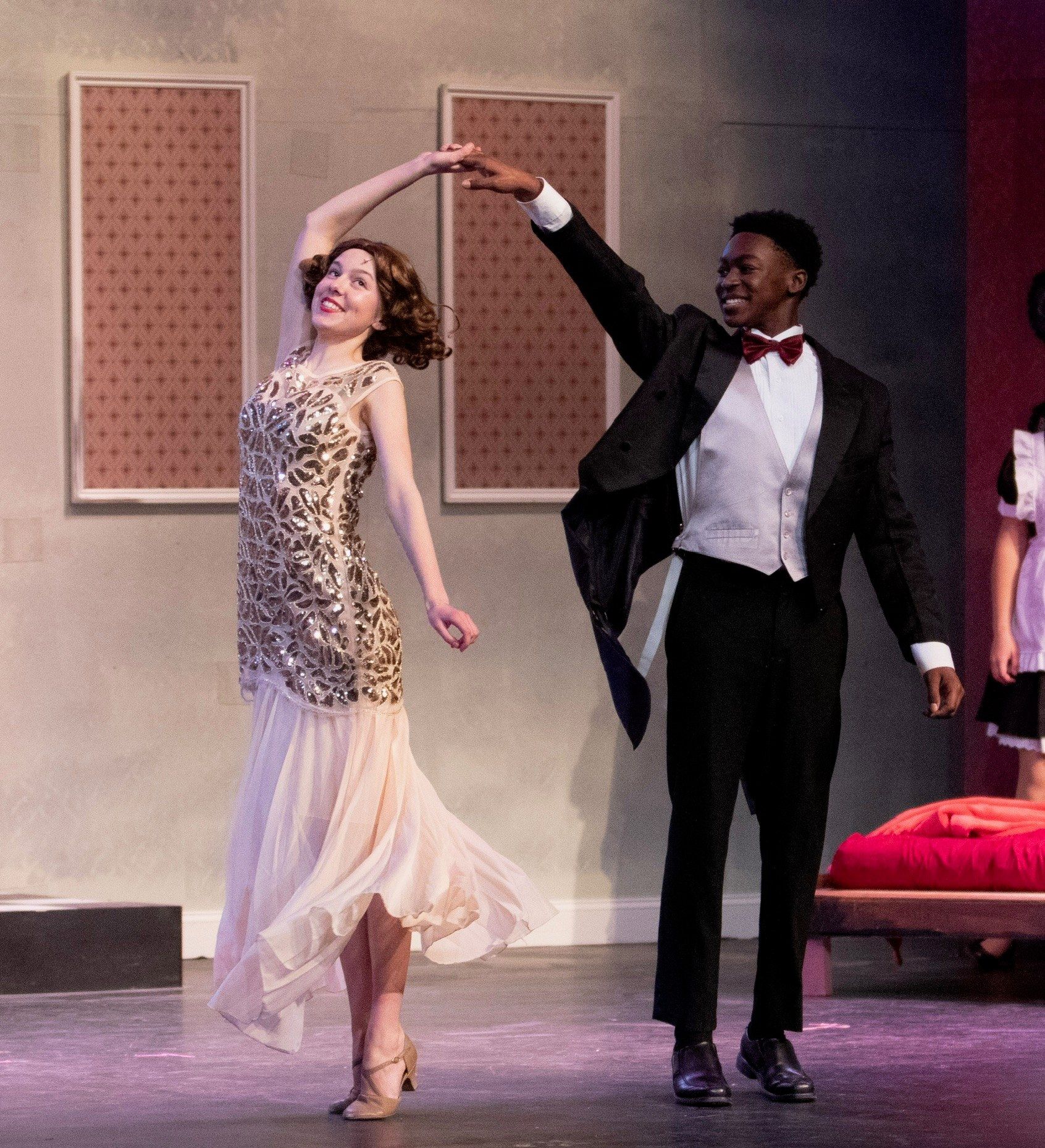 Amelie Lock in a cream beaded gown, mid-turn, her hand raised to meet her dance partner’s, in The Drowsy Chaperone