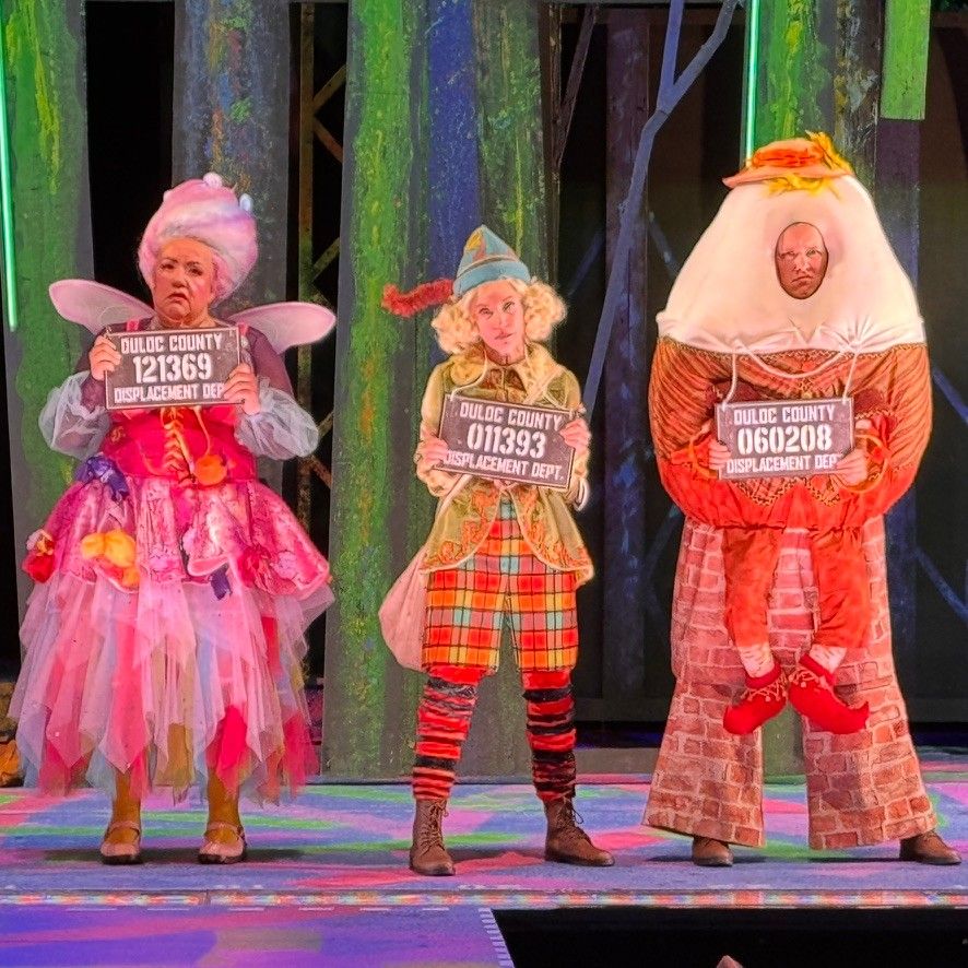 A fairy godmother, a gnome and Humpty Dumpty holding Duloc County displacement department number plates, in Shrek The Musical at The Muny