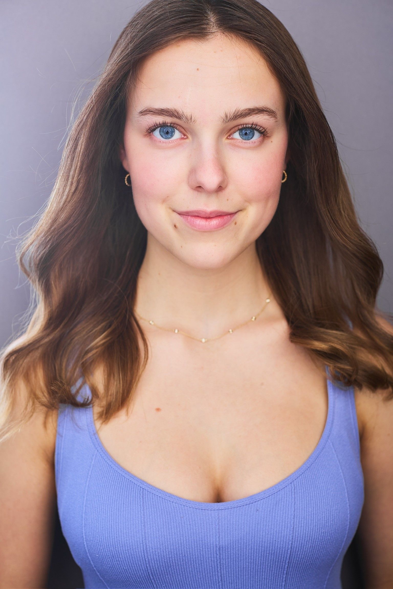 Amelie Lock in a lilac top, looking into the camera with a slight smile, against a gray backdrop